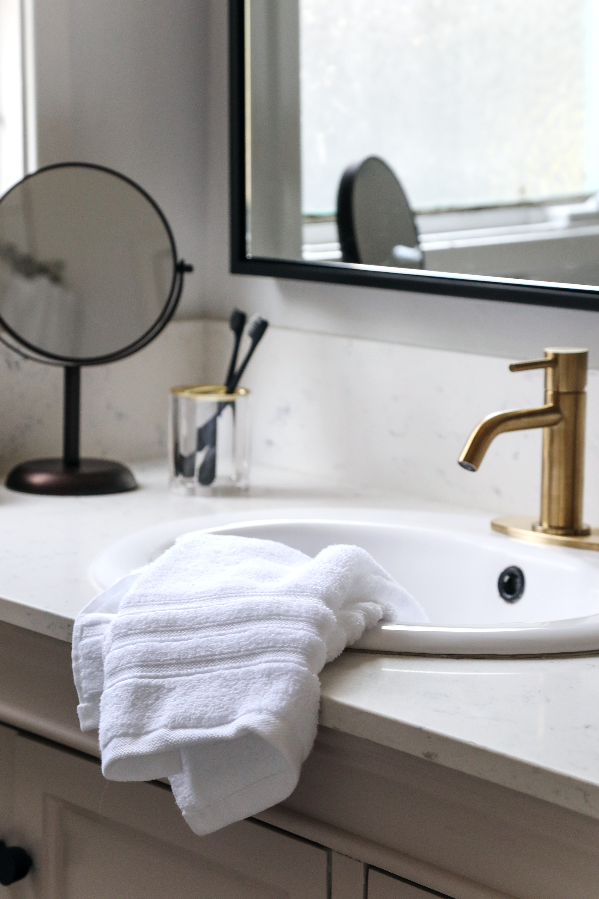 budget bathroom makeover with brass fixtures and black mirror